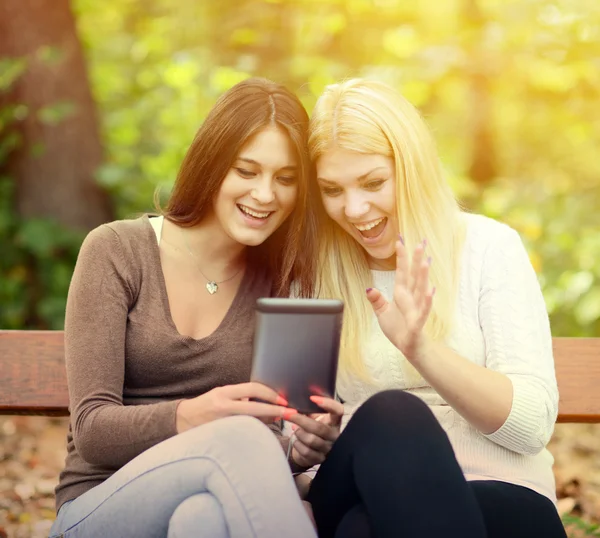 Deux jeunes femmes regardant tablette et chating en ligne avec un ami — Photo