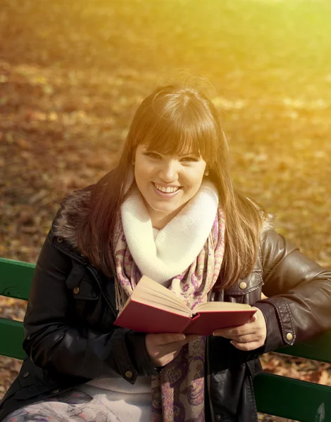 Studentessa lettura libro su panchina in autunno foresta — Foto Stock