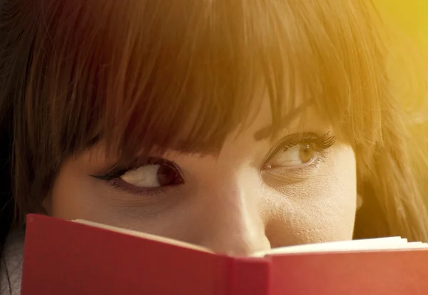 Hermosa chica escondiéndose detrás de un libro — Foto de Stock
