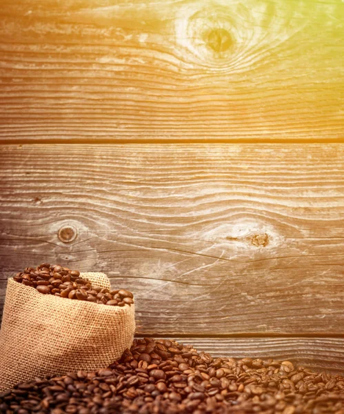 Sack of coffee grains against wooden background — Stock Photo, Image