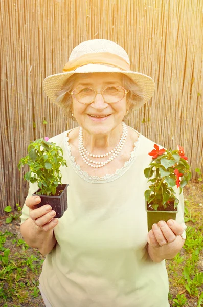 Happy senior kvinna med blommor i trädgården — Stockfoto