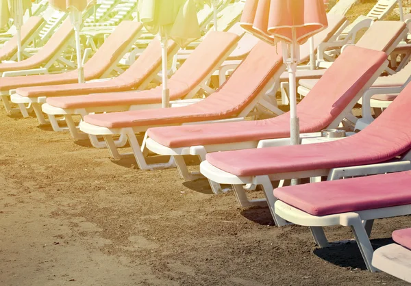 Camas de sol cor de rosa na praia — Fotografia de Stock