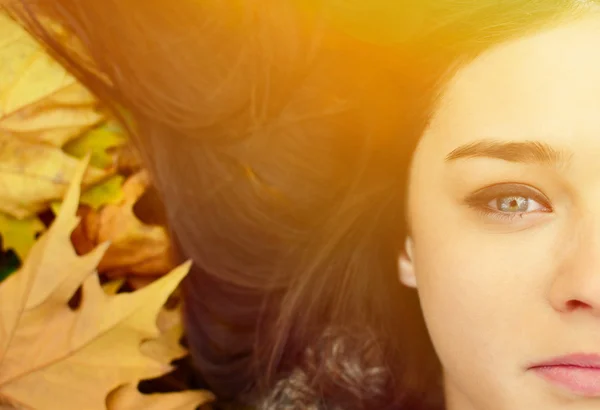 Femme visage couché sur les feuilles d'automne — Photo