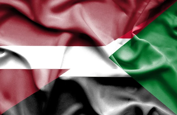 Waving flag of Sudan and Latvia — Stock Photo, Image