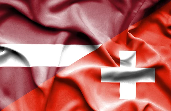 Wapperende vlag van Zwitserland en Letland — Stockfoto