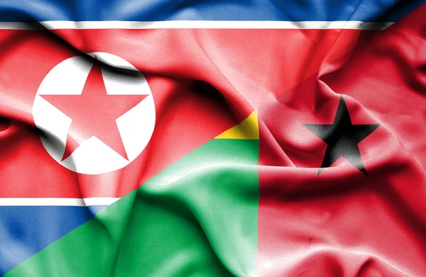 Flagge von Guinea-Bissau und Nordkorea schwenken — Stockfoto