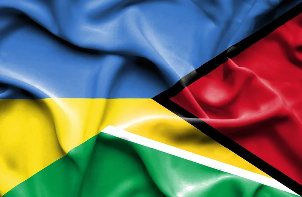 Flagge von Guyana und der Ukraine schwenkend — Stockfoto