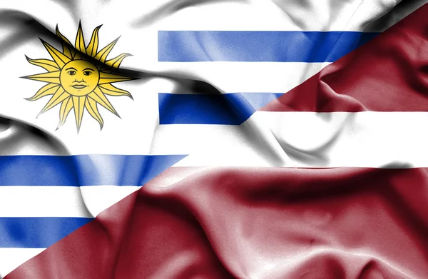 Waving flag of Latvia and Uruguay — Stockfoto