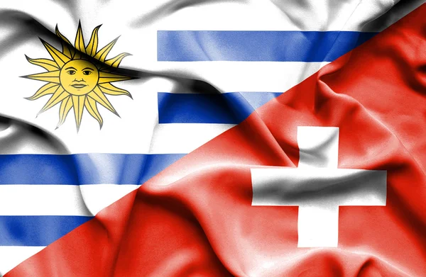 Waving flag of Switzerland and Uruguay — Stockfoto