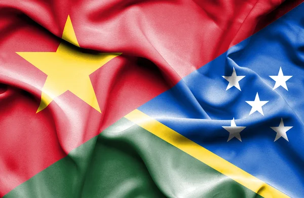 Waving flag of Solomon Islands and Vietnam — Stockfoto