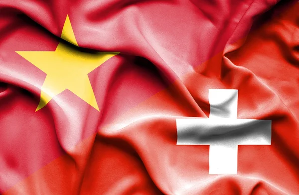 Waving flag of Switzerland and Vietnam — стокове фото