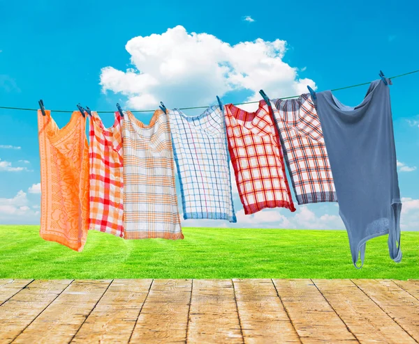 Laundry hanging over flower field with wooden floor — Stock Photo, Image