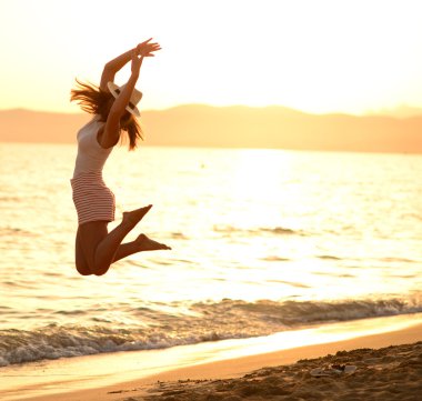 mutlu bir kadın deniz günbatımı atlama