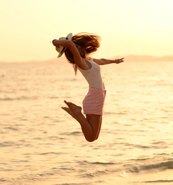 Mujer feliz saltando en la puesta del sol del mar — Foto de Stock