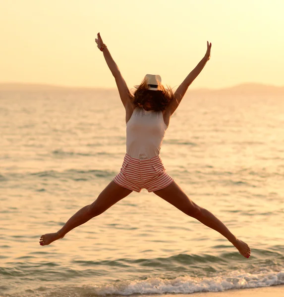 Glückliche Frau springt in Meer Sonnenuntergang — Stockfoto