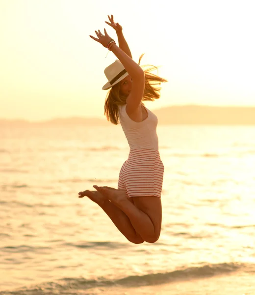 Mujer feliz saltando en la puesta del sol del mar — Foto de Stock