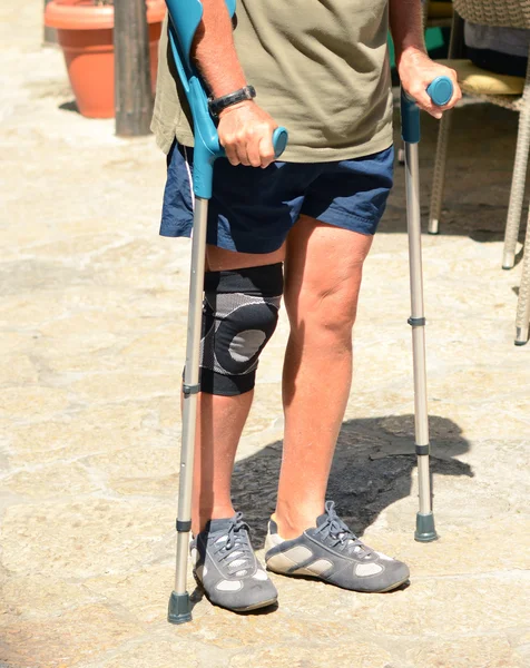Hombre caminando con muletas, rehabilitación después de una lesión —  Fotos de Stock