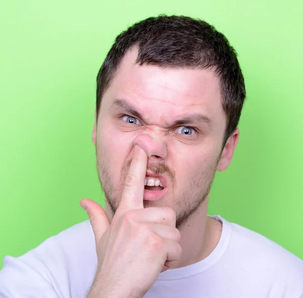 Portrait of a funny guy with finger in his nose against green ba — Stock Photo, Image