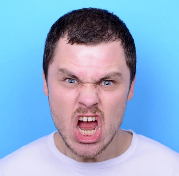 Portrét rozhněvaný muž křičí a tahání za vlasy proti modré ba — Stock fotografie