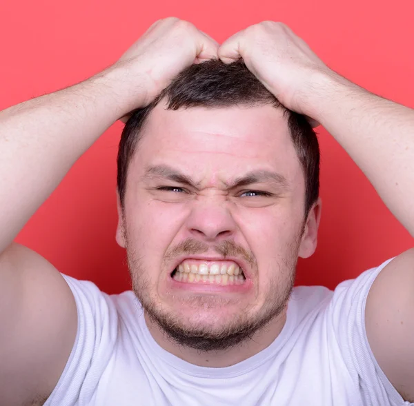 Портрет розлюченого чоловіка, що кричить і тягне зачіску проти червоного спини — стокове фото