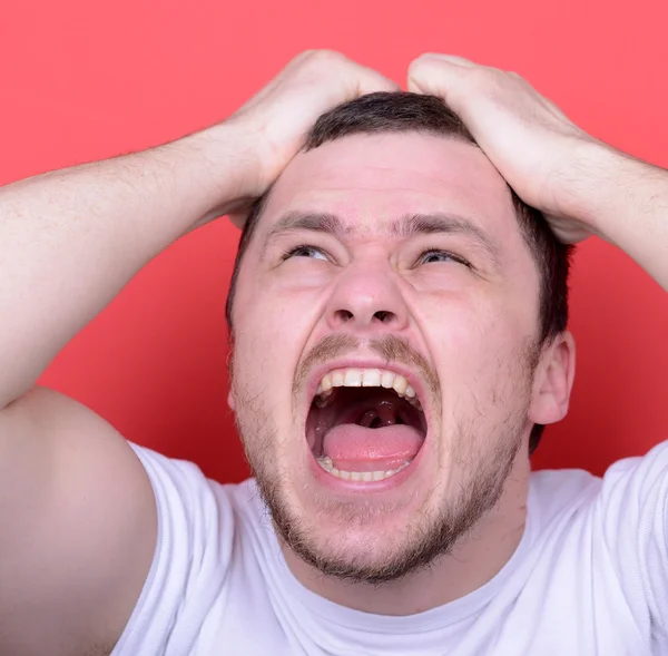 Retrato de hombre enojado gritando y tirando de pelo contra bac rojo —  Fotos de Stock