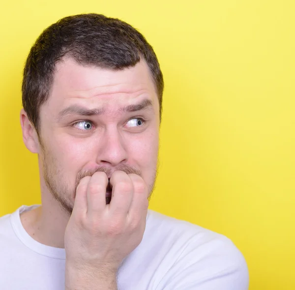 Portrait of man biting nails against yellow background — Stock Photo, Image