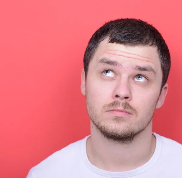 Portrait of man thinking and looking up against red background — Stock Photo, Image