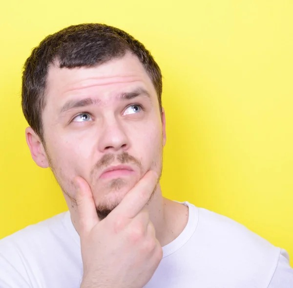 Retrato del hombre pensando y mirando hacia arriba contra el fondo amarillo — Foto de Stock