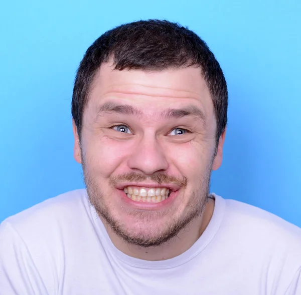 Portret van man met grappige gezicht tegen blauwe achtergrond — Stockfoto