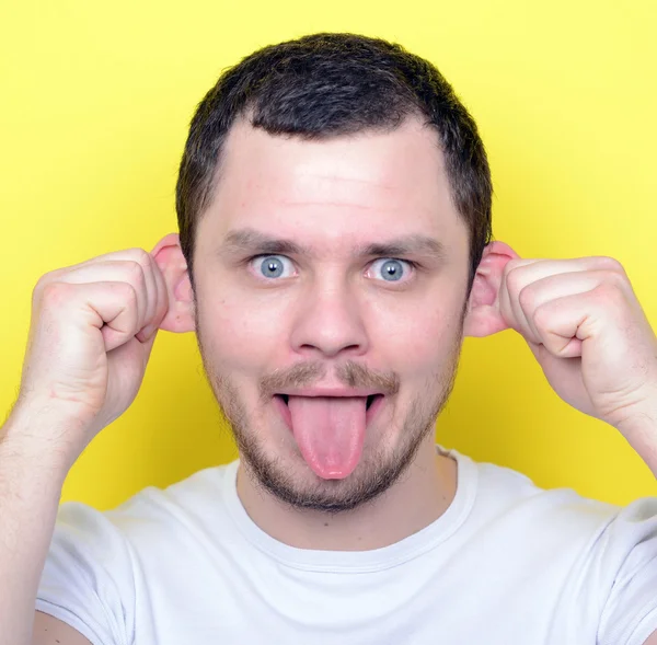Portrait of man with funny face against yellow background — Stok Foto