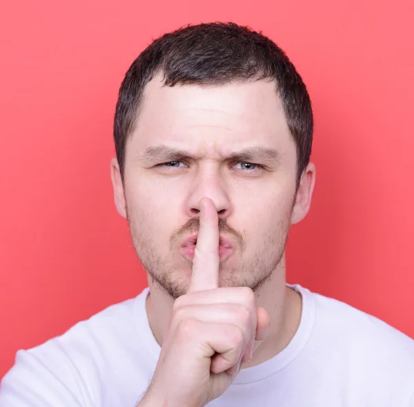 Portrait of man with gesture for silence against red background — Stock Photo, Image