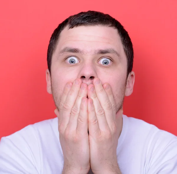 Portrait of man with hands covering mouth against red background — Stock Photo, Image