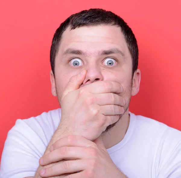 Portret van de man met de handen die betrekking hebben op mond tegen rode achtergrond — Stockfoto