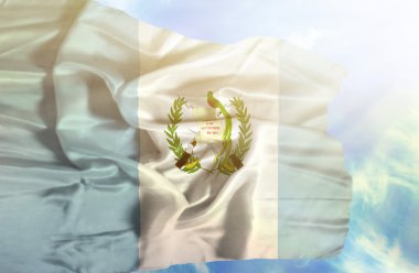 Mavi gökyüzü ile yapraklara karşı bayrak sallayarak guatemala