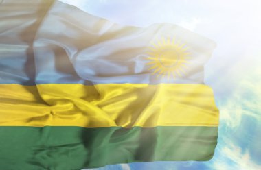 Mavi gökyüzü ile yapraklara karşı bayrak sallayarak Ruanda
