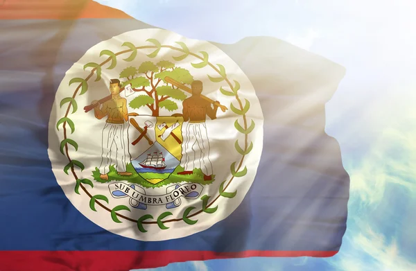 Belize schwenken Flagge gegen blauen Himmel mit Sonnenstrahlen — Stockfoto