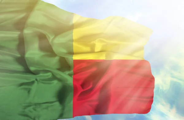 Drapeau du Bénin agitant contre le ciel bleu avec des rayons de soleil — Photo