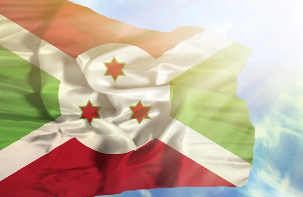 Burundi waving flag against blue sky with sunrays — Stock Photo, Image