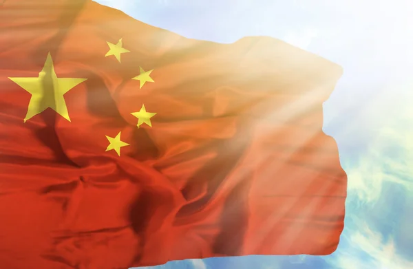Китай машет флагом на фоне голубого неба с солнечными лучами — стоковое фото