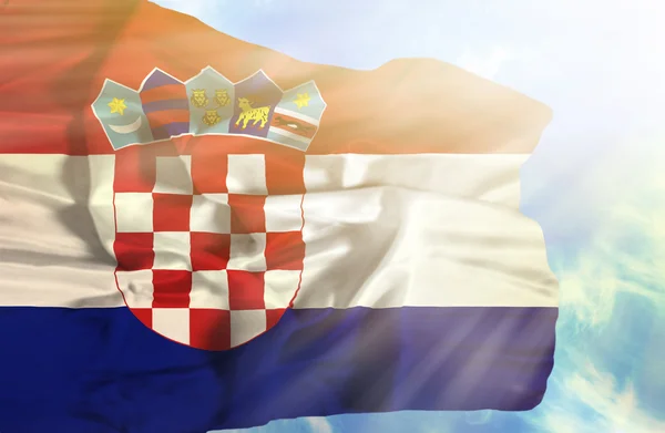 Kroatië zwaaien vlag tegen blauwe hemel met zonnestralen — Stockfoto