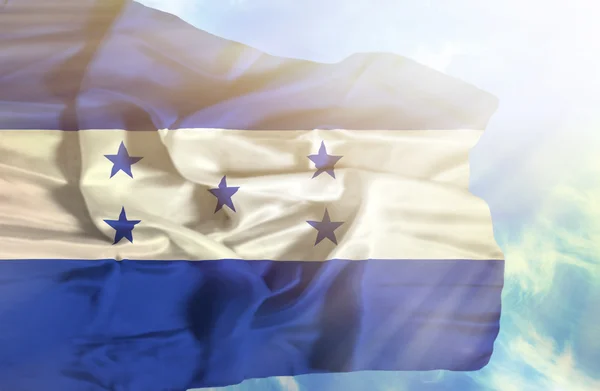 Honduras viftande flagga mot blå himmel med solstrålar — Stockfoto