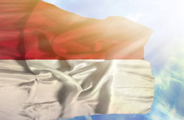 Indonesien schwenkt Flagge gegen blauen Himmel mit Sonnenstrahlen — Stockfoto