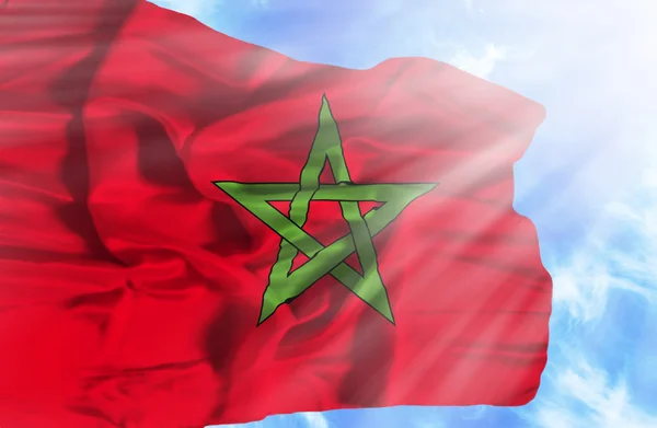 Marocco waving flag against blue sky with sunrays — Stock Photo, Image