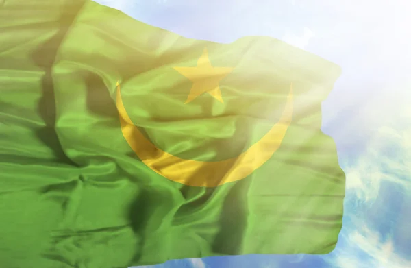 Mauritanie agitant le drapeau contre le ciel bleu avec des rayons de soleil — Photo