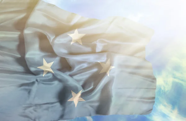 Mikronésie mává vlajkou proti modré obloze se slunečními paprsky — Stock fotografie