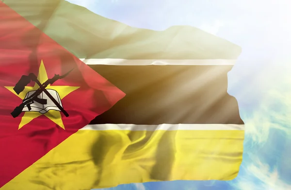 Mozambique ondeando bandera contra el cielo azul con rayos de sol — Foto de Stock