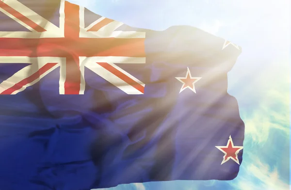 New Zealand waving flag against blue sky with sunrays — Stock Photo, Image