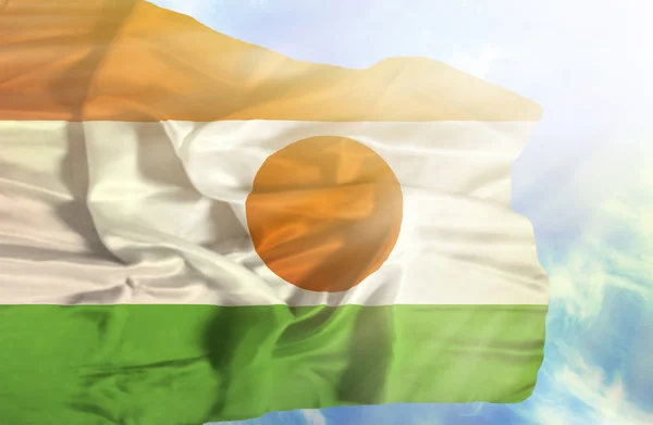 Níger ondeando bandera contra el cielo azul con rayos de sol —  Fotos de Stock