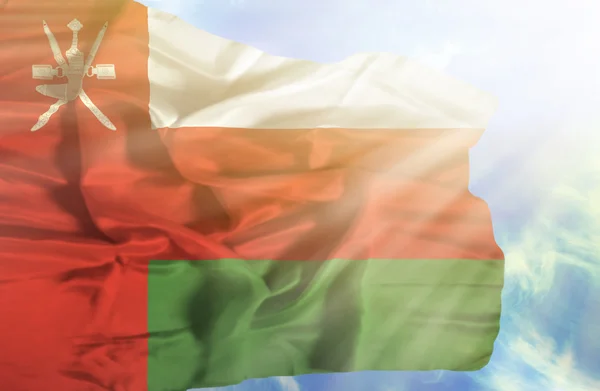 Oman vinker flag mod blå himmel med solstråler - Stock-foto