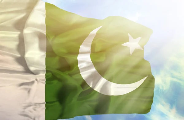 Pakistan schwenkt Flagge gegen blauen Himmel mit Sonnenstrahlen — Stockfoto